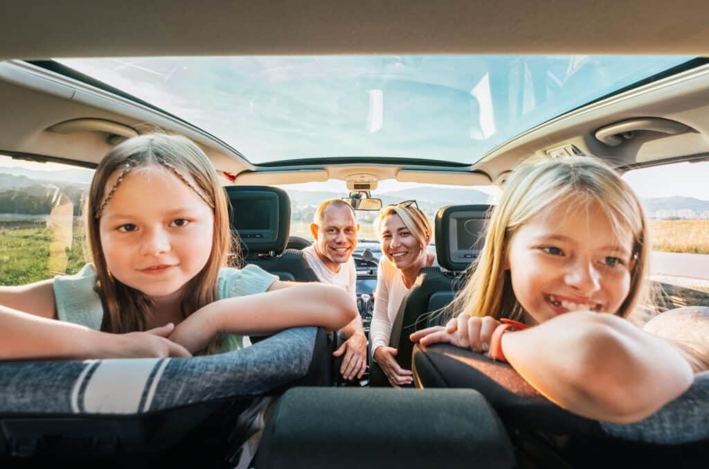Young couple and daughters in family car
