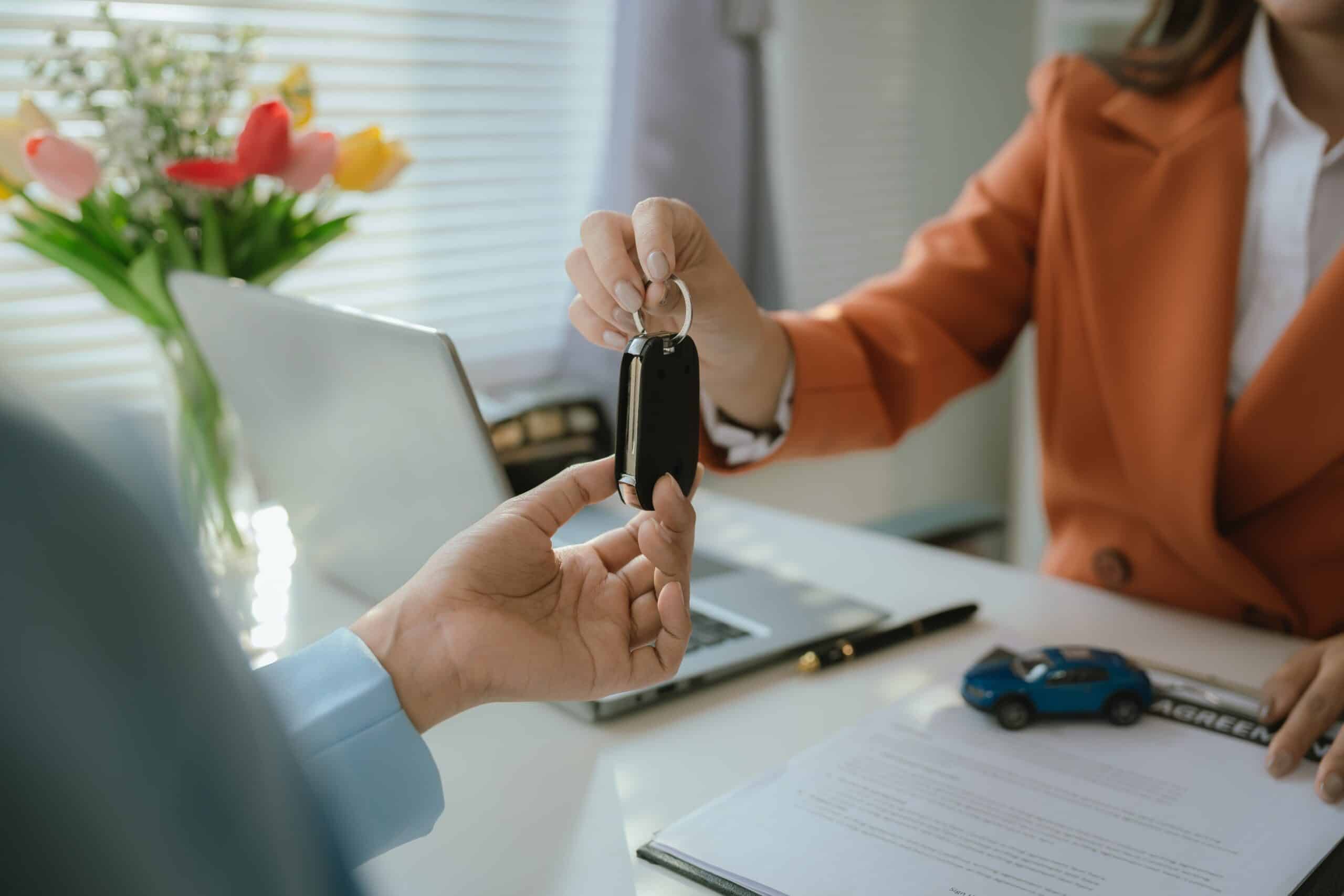 Salesperson hands car keys to new car owner