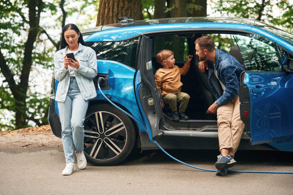 family waiting for a blue electric car to finish charging for free