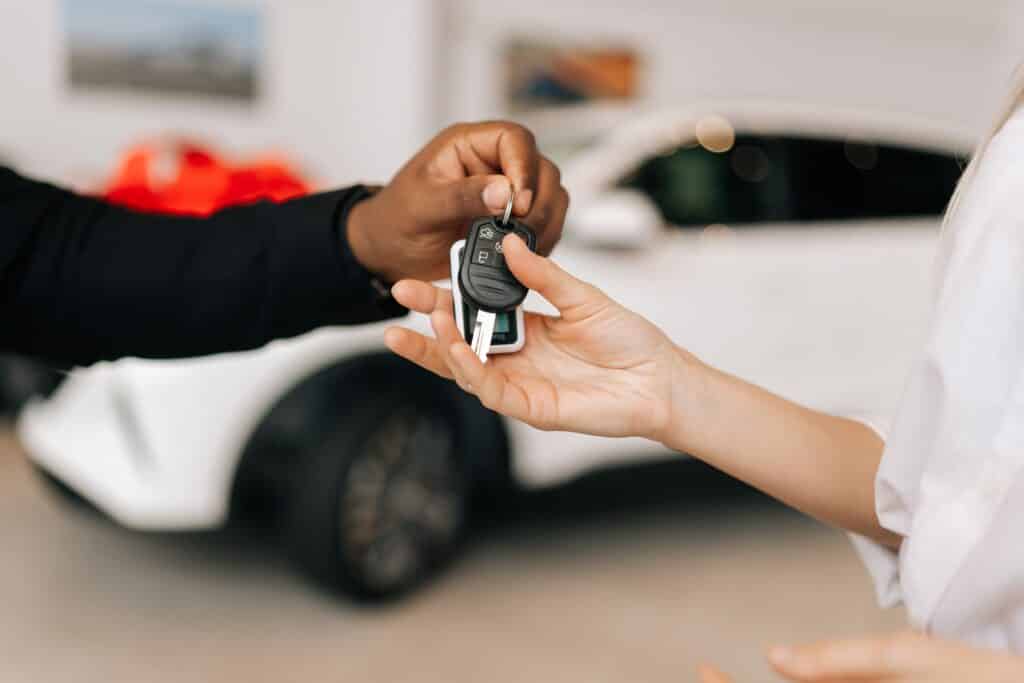 Man handing woman keys to new car